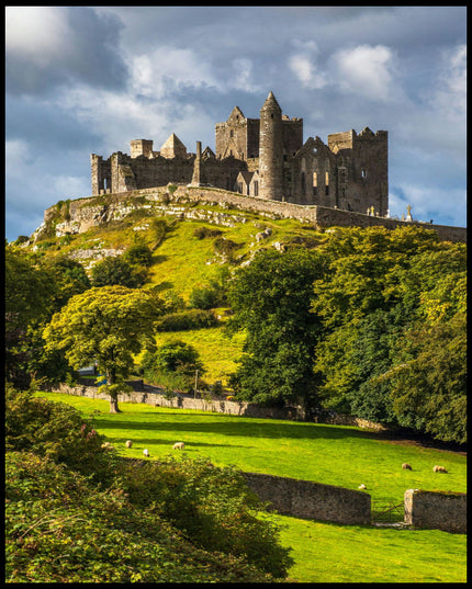 Ein Leinwandbild von den Ruinen des Rock of Cashel auf einem Hügel in Irland, umgeben von grünen Wiesen und Bäumen.