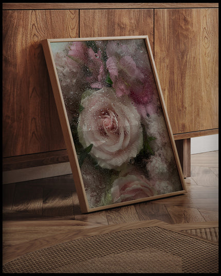 Ein gerahmtes Poster von zarten rosa und weißen Blumen hinter einer Glasscheibe, die von Wassertropfen bedeckt sind, an einer Holzkommode angelehnt und stehend auf dem Holzboden