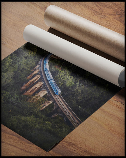 Ein Poster von einem blauen Zug, der über eine alte Brücke inmitten eines grünen Waldes fährt, gerollt auf einer Holzoberfläche liegend