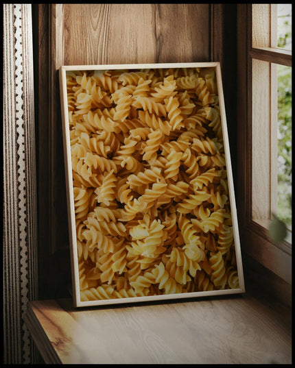 Ein gerahmtes Poster von vielen Fusilli Nudeln, vor einem Fenster an die Wand angelehnt