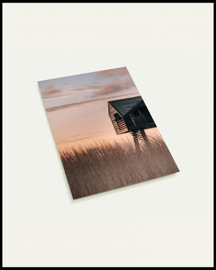 Eine Postkarte von einer Hütte am Strand in den Dünen bei Sonnenuntergang.